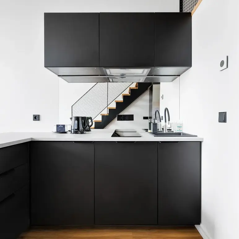 a kitchen with black cabinets and a staircase