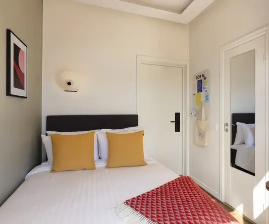 a bed with pillows and a red rug in a room