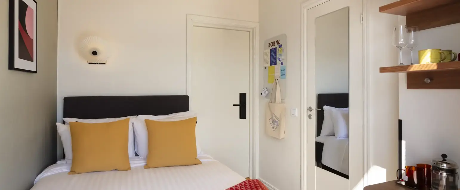 a bed with pillows and a red rug in a room