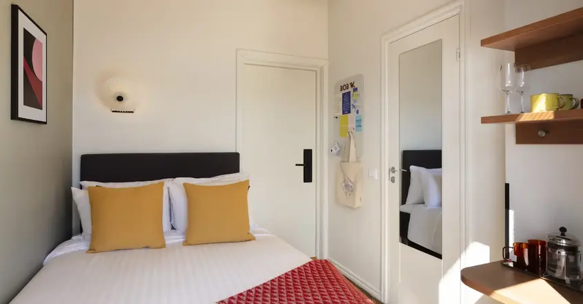 a bed with pillows and a red rug in a room