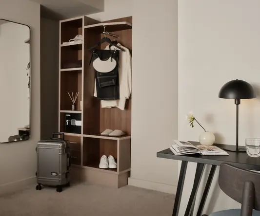 a room with a desk and a chair and a table with a suitcase