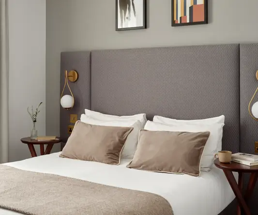 a bed with pillows and a table with artwork above it