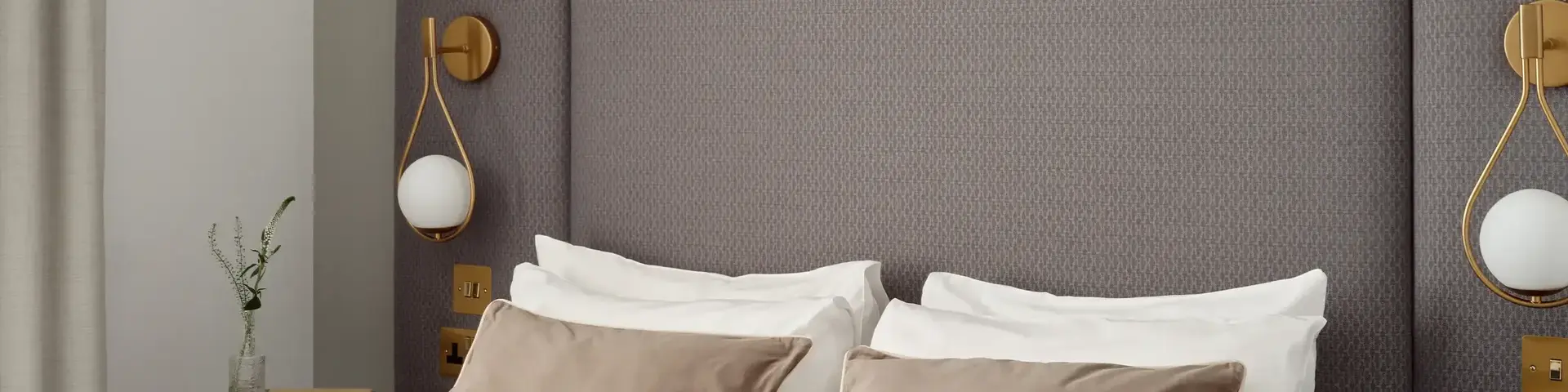 a bed with pillows and a table with artwork above it