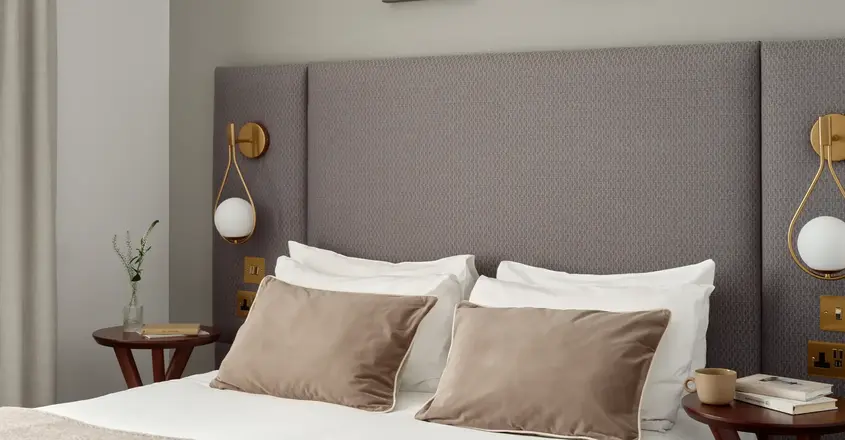 a bed with pillows and a table with artwork above it