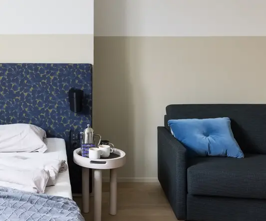 a bed with a blue headboard and coffee cups on a table