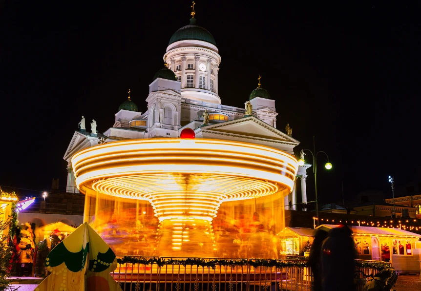 A spinning carousel in light trails in front of Helsinki Cathedral at night