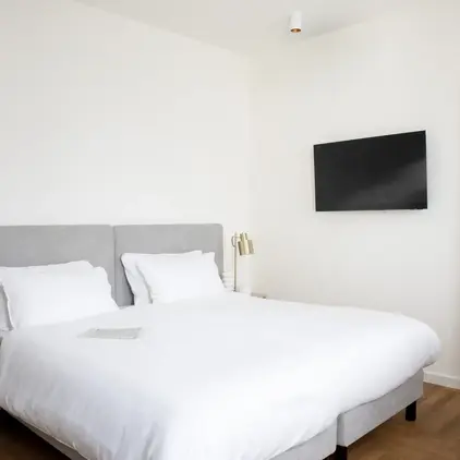 a bed with a tv on the wall