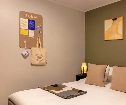 a bed with pillows and a lamp on the wall