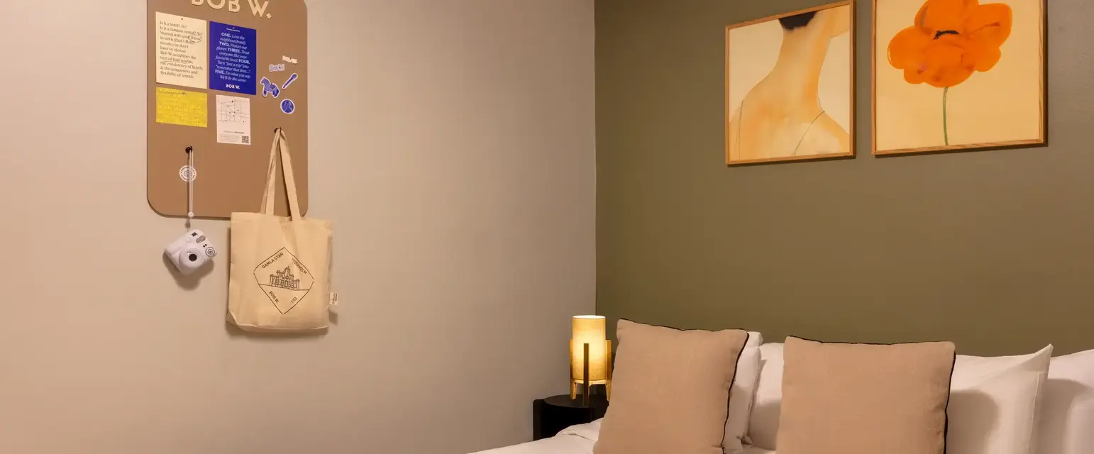 a bed with pillows and a lamp on the wall