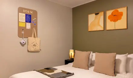 a bed with pillows and a lamp on the wall