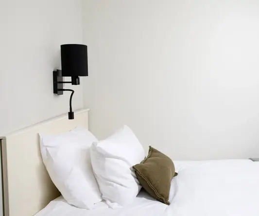 a bed with white sheets and pillows