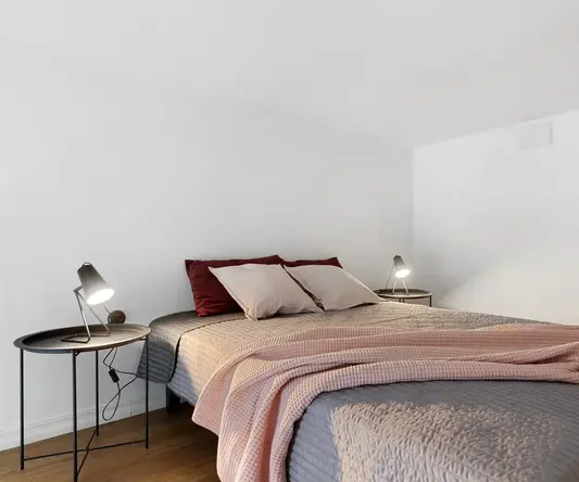 a bed with a pink blanket and two lamps