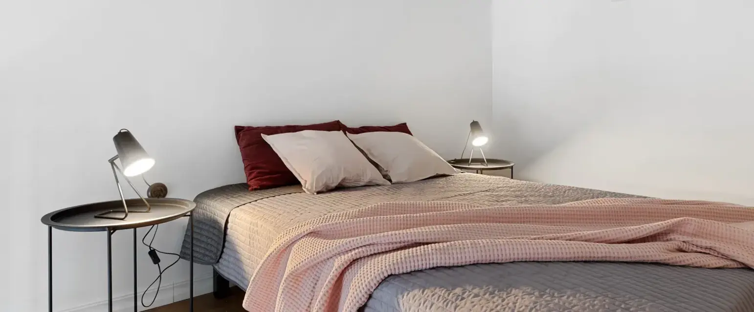 a bed with a pink blanket and two lamps
