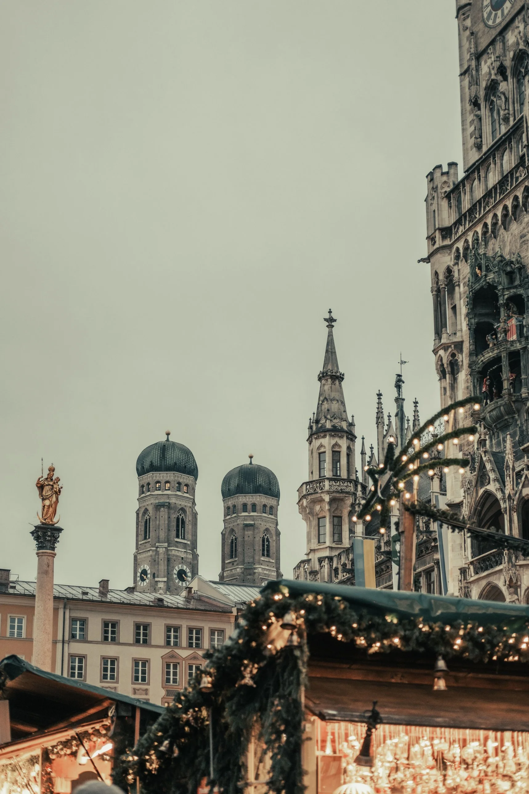 The Frauenkirche towers and New Town Hall above a garland-covered market stall on Marienplatz