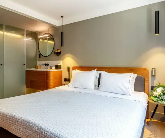 a bed with white sheets and a mirror in a room