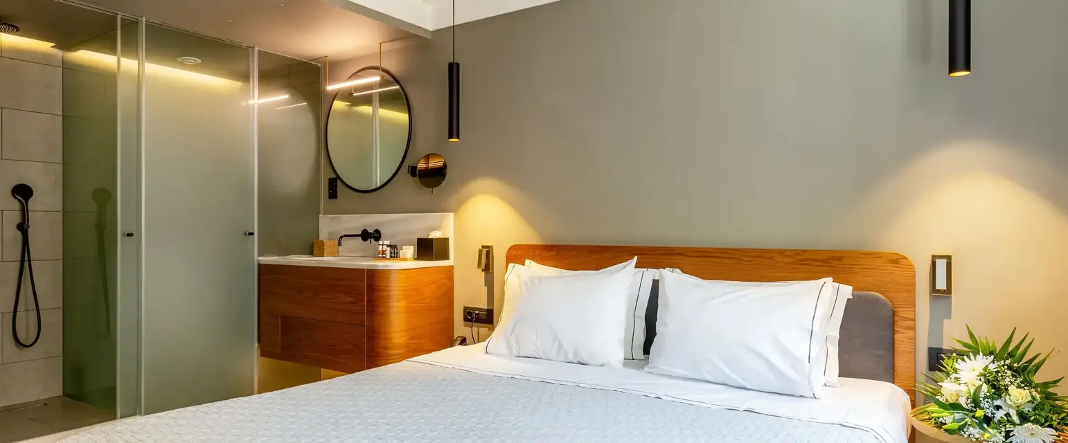 a bed with white sheets and a mirror in a room