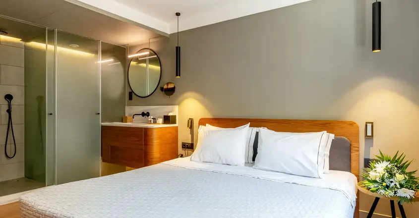 a bed with white sheets and a mirror in a room