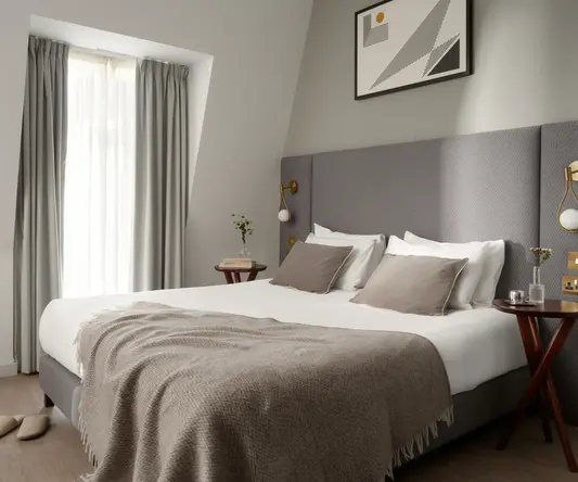 a bed with a blanket and a picture on the wall