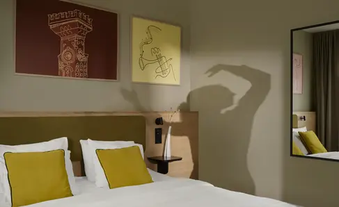 a bed with yellow pillows and a mirror in a room