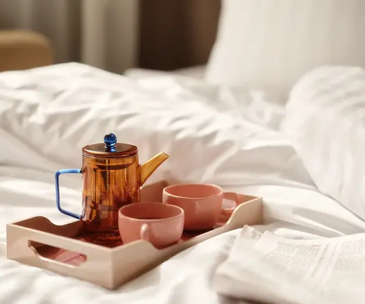 a tray with tea set and cups on a bed