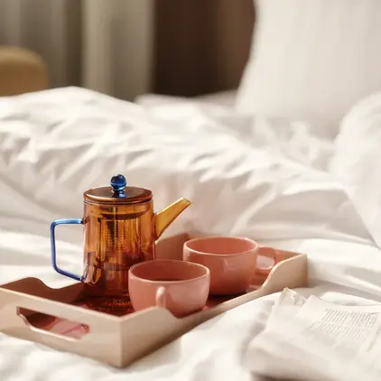 a tray with tea set and cups on a bed