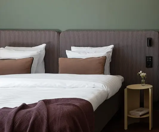 a bed with striped bedding and a table with a lamp