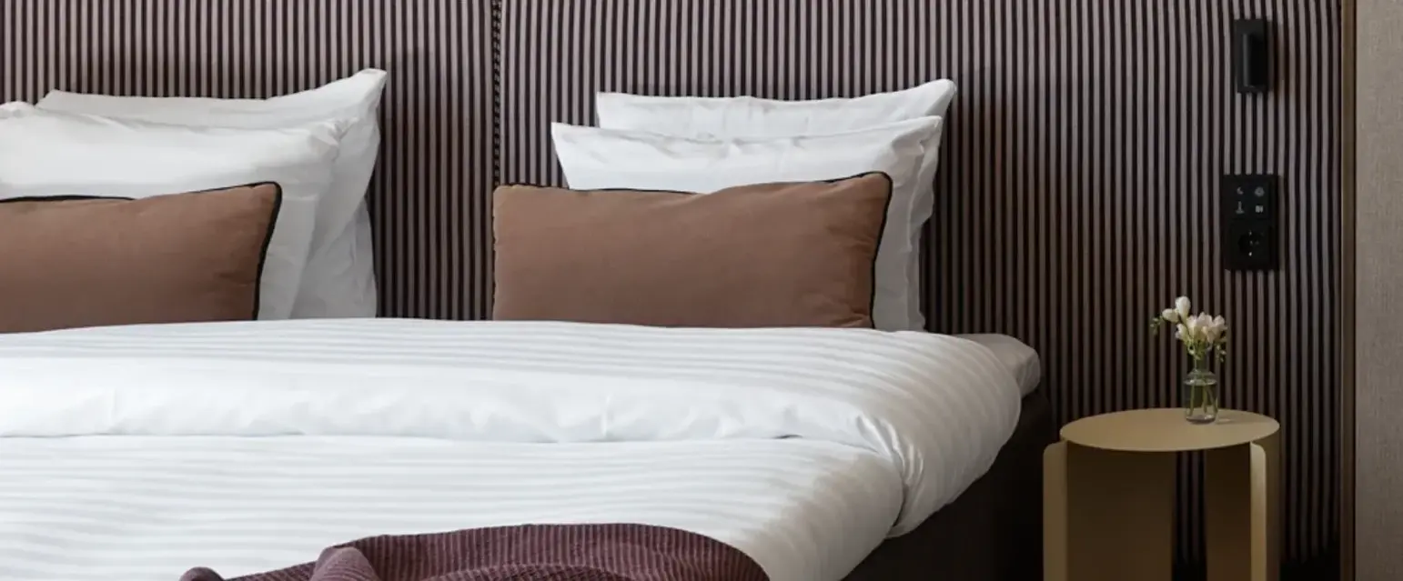 a bed with striped bedding and a table with a lamp