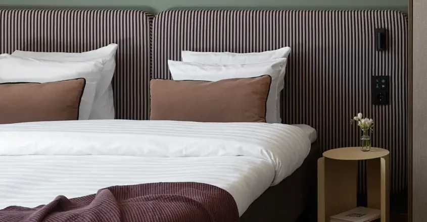 a bed with striped bedding and a table with a lamp