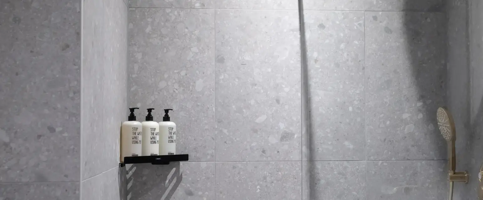 a shower with a couple of white bottles on a shelf