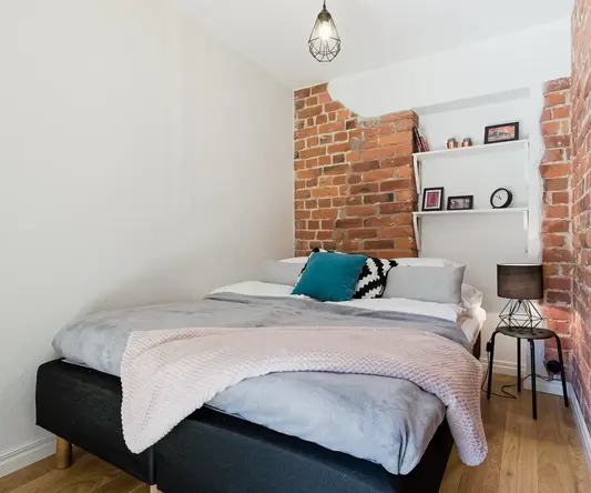 a bed with a brick wall behind it