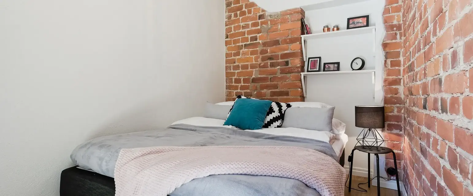 a bed with a brick wall behind it
