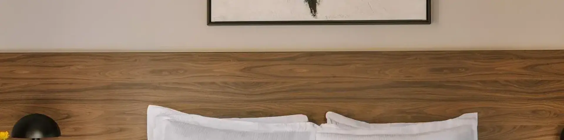 a bed with white sheets and a painting on the wall