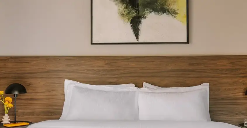 a bed with white sheets and a painting on the wall