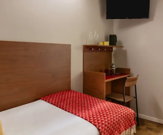 a bed with a red blanket and a wood headboard in a room