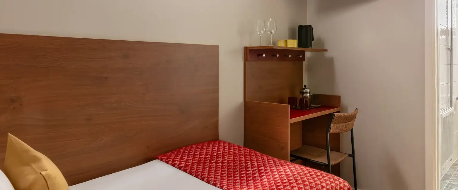 a bed with a red blanket and a wood headboard in a room