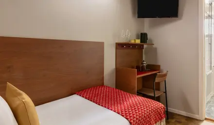 a bed with a red blanket and a wood headboard in a room