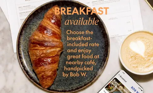 a croissant on a plate next to a phone and a cup of coffee