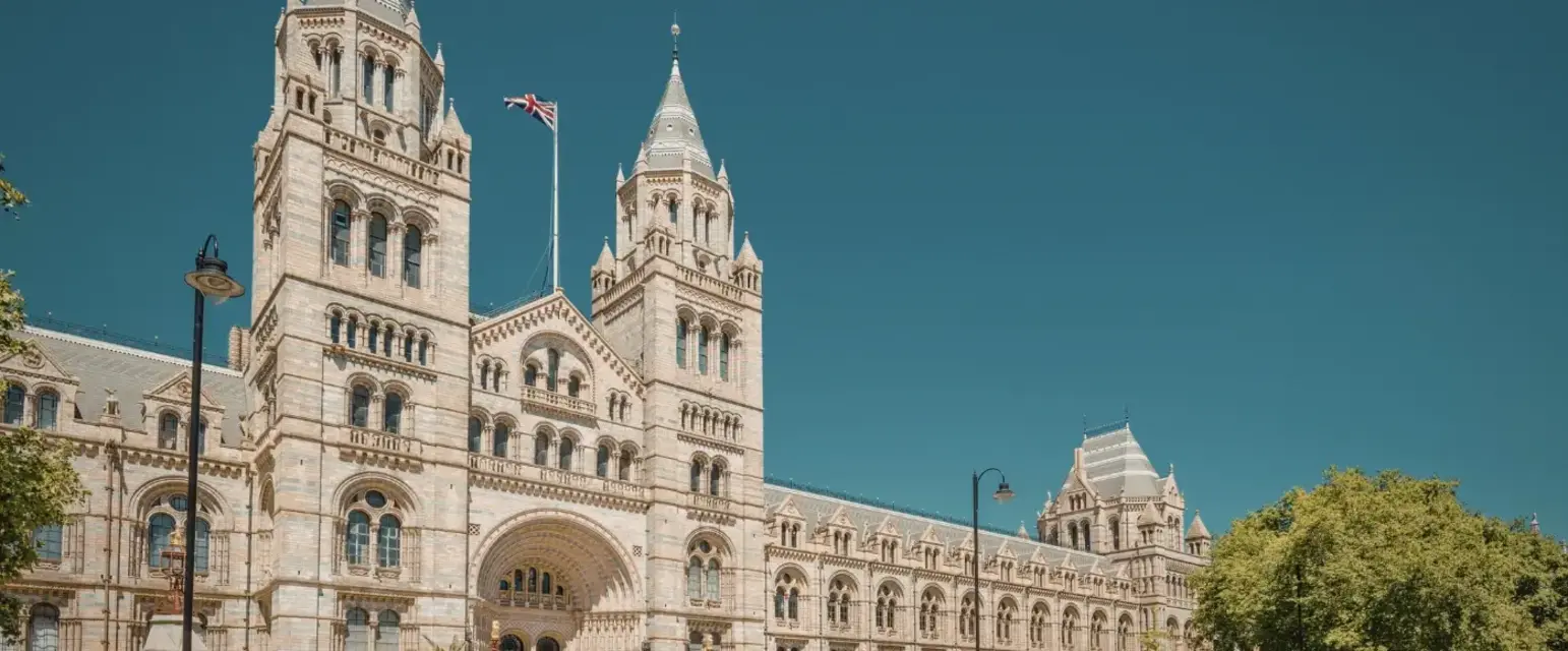 a large building with a flag on top with Natural History Museum in the background