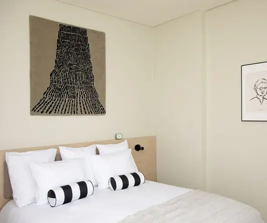 a bed with pillows and a picture on the wall