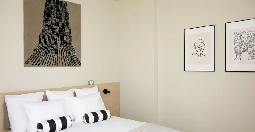 a bed with pillows and a picture on the wall