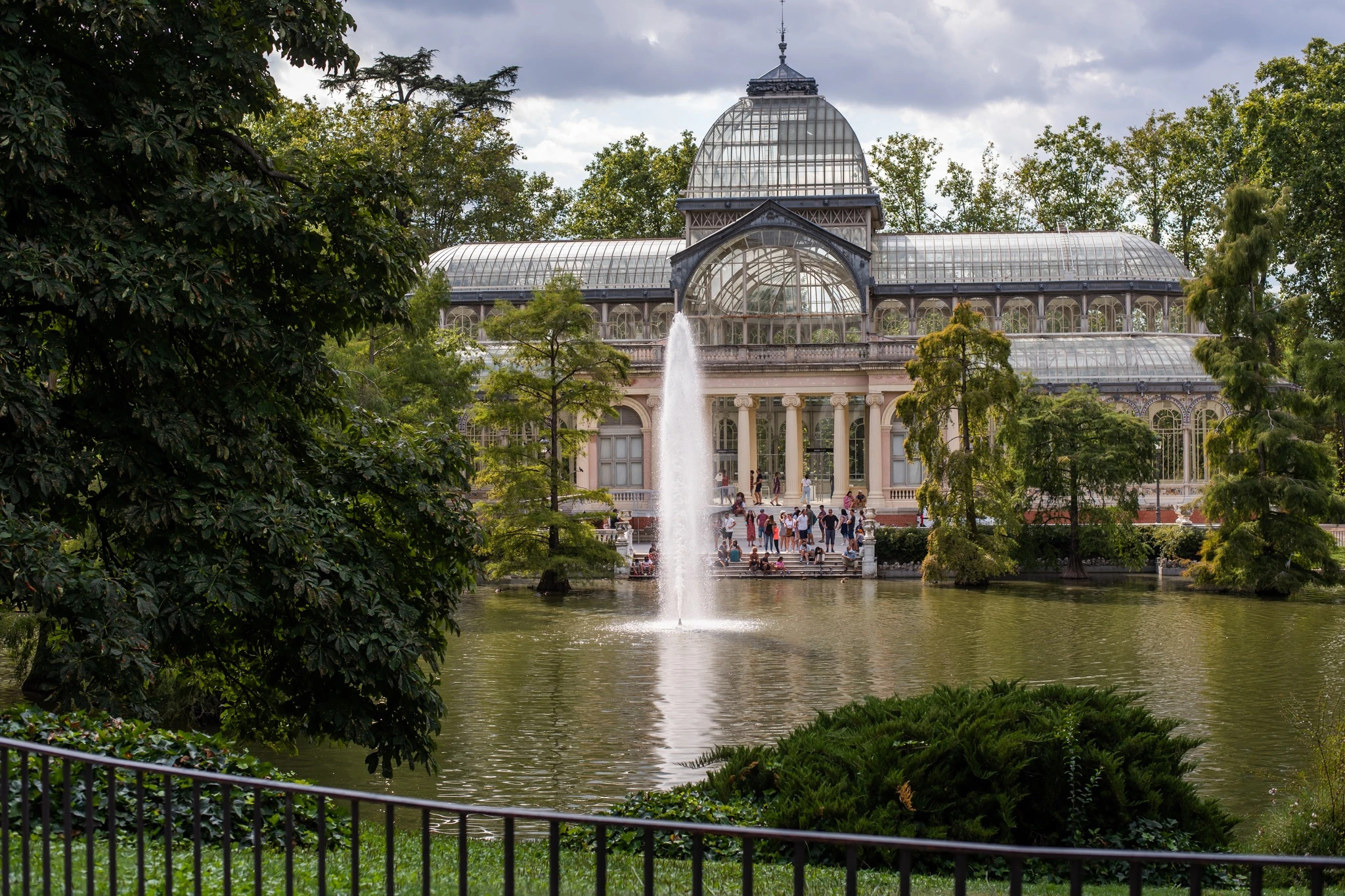 The Palacio de Cristal and its fountain on the lake in Retiro Park.