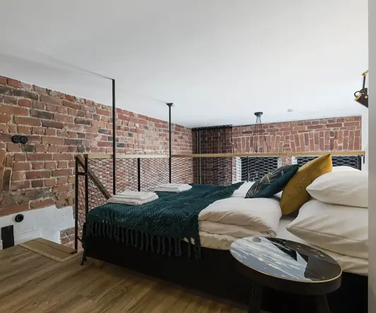 a bed with a metal railing and a brick wall