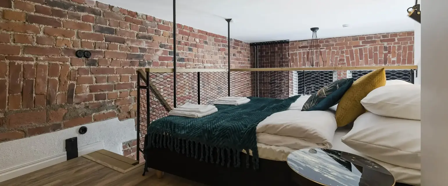 a bed with a metal railing and a brick wall