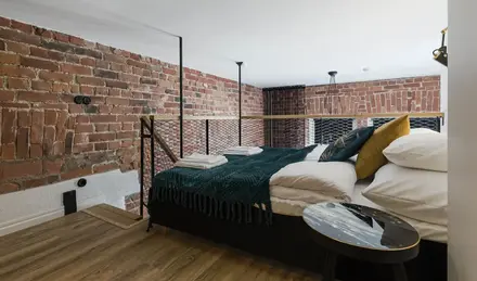 a bed with a metal railing and a brick wall