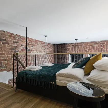 a bed with a metal railing and a brick wall