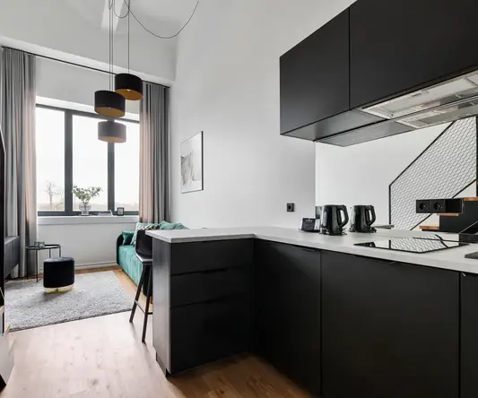 a kitchen with black cabinets and a green couch