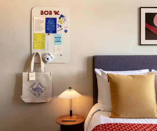 a bed with pillows and a lamp on a table