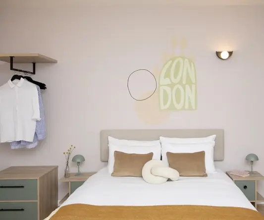 a bed with pillows and a lamp on the wall