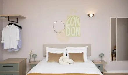 a bed with pillows and a lamp on the wall