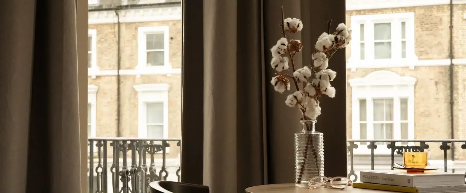 a vase with cotton flowers on a table
